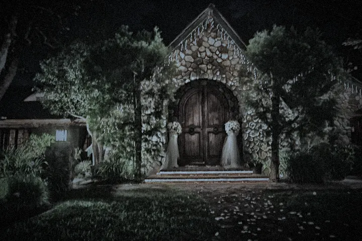 The arched doors of the manor lit at night