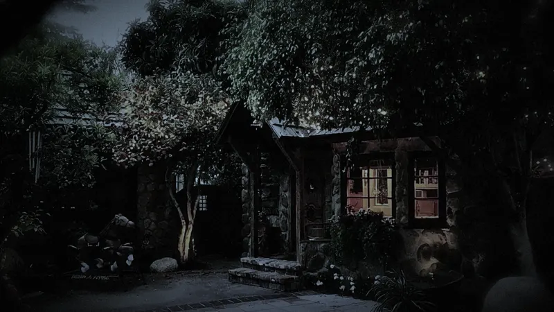 The stone cottage glowing through the trees at night